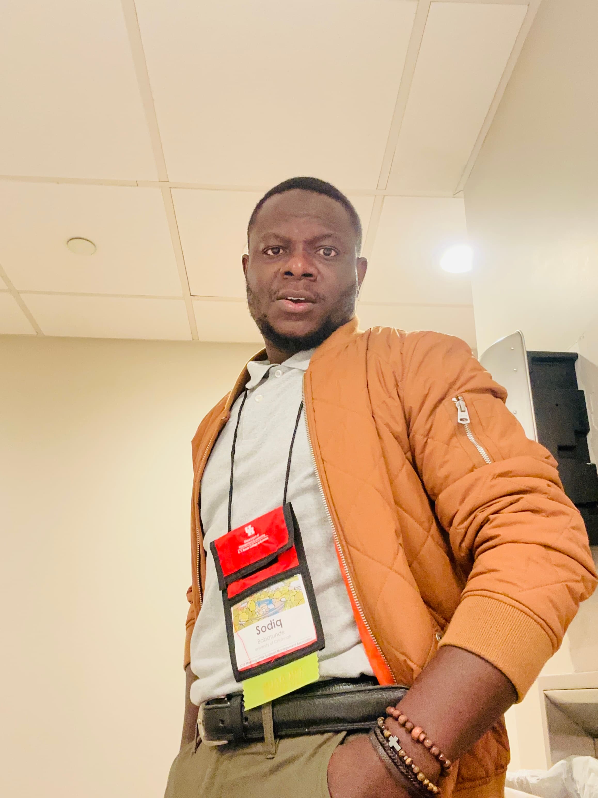 Sodiq Babatunde between sessions at a management conference, wearing his attendee badge